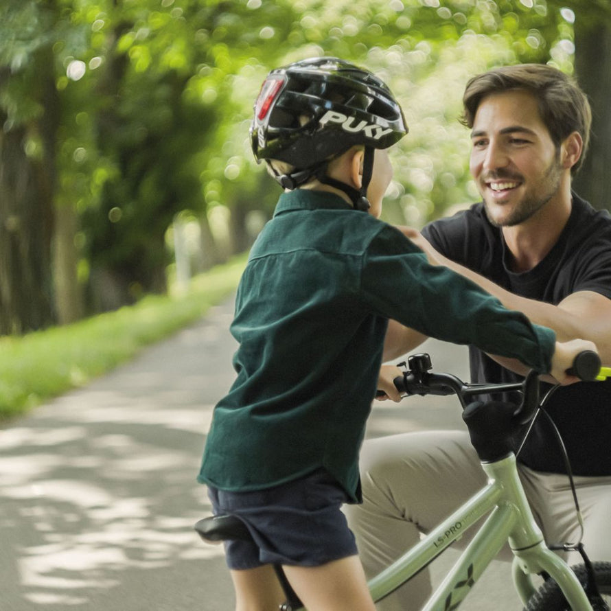 Enfant souriant apprenant à rouler sur le vélo PUKY LS-PRO 14, cadre ergonomique et freins colorés