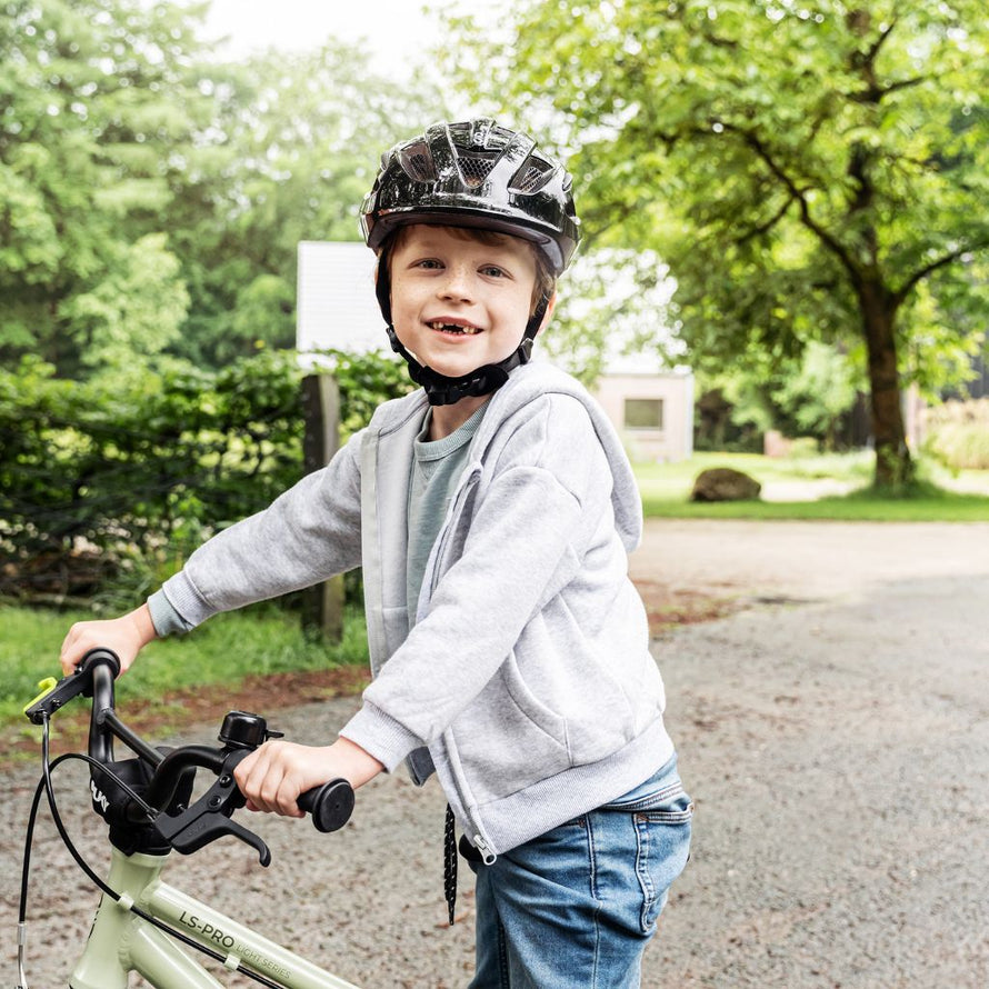 Enfant souriant avec son vélo PUKY LS-PRO 16 vert sur un chemin, sécurité et plaisir des premières sorties