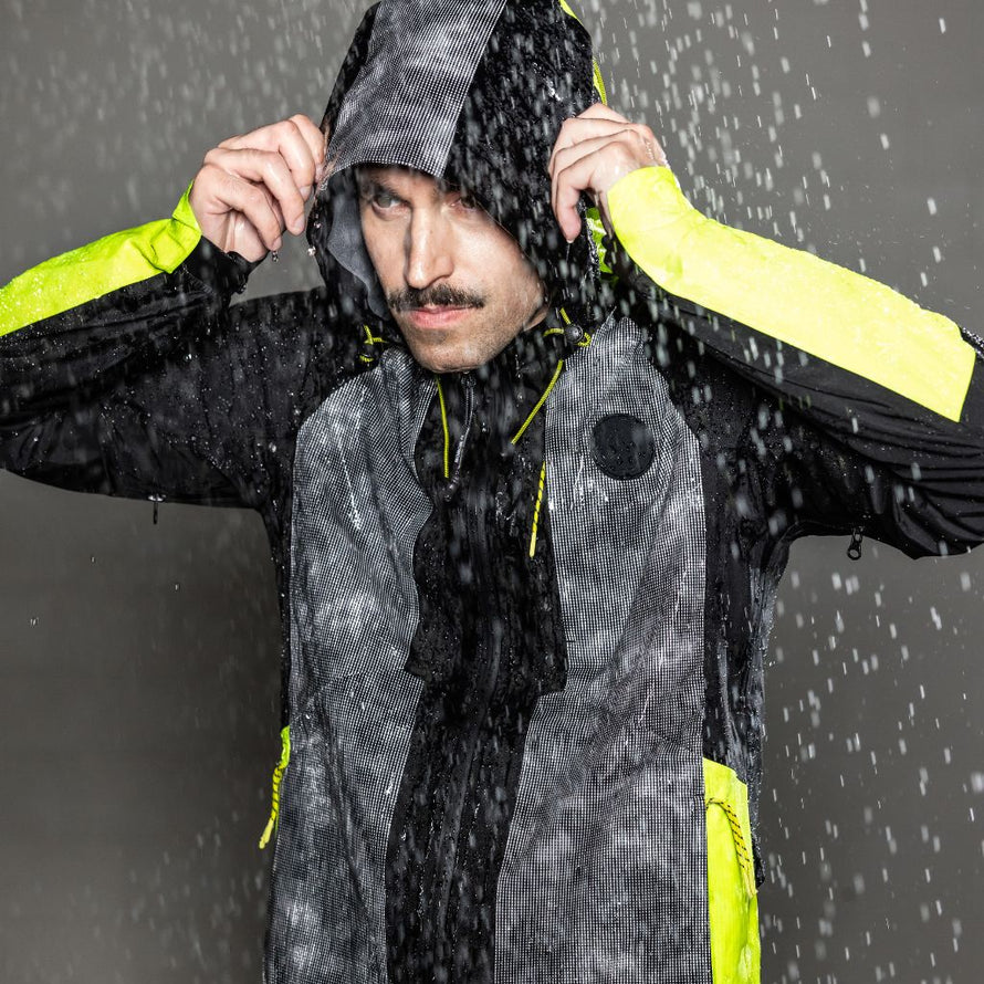 Cycliste en pleine pluie avec la veste Wowow Etna, équipement technique, respirant et étanche pour une visibilité maximale à vélo.