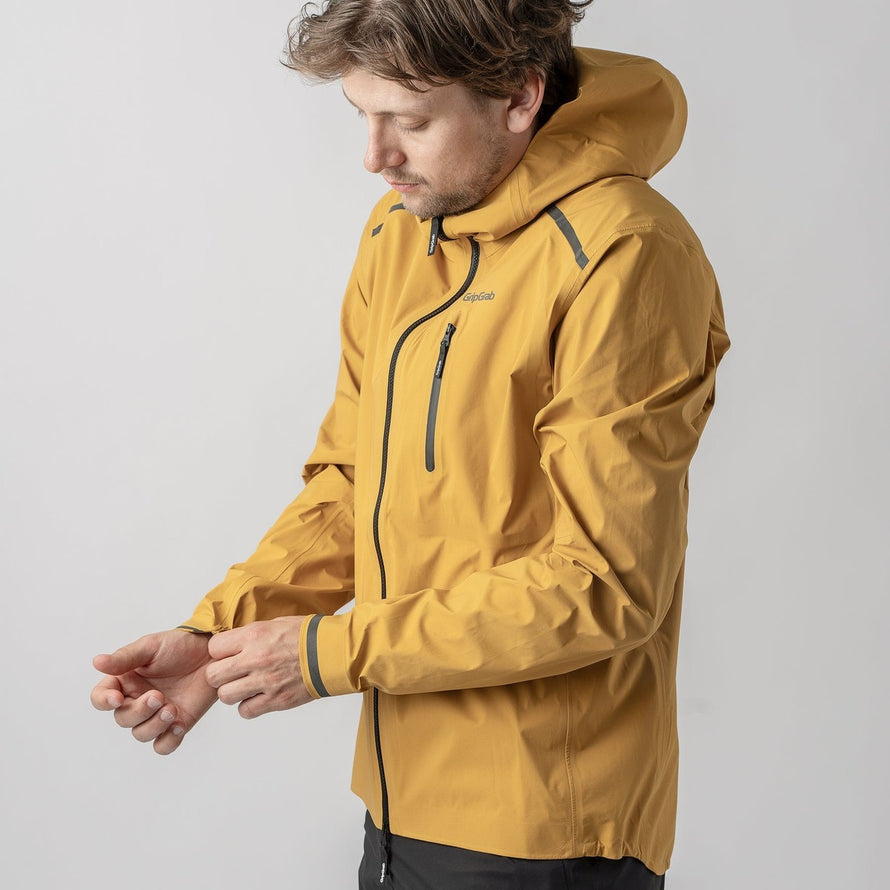 Veste imperméable vélo Explr GripGrab moutarde avec capuche, coupe homme, protection pluie et détails réfléchissants