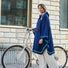 Femme portant un poncho bleu Imbris Weathergoods Sweden, debout avec son vélo urbain, prête pour ses trajets quotidiens.