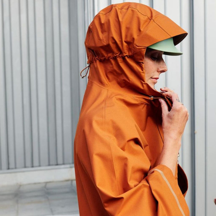 Gros plan sur une femme portant le poncho cuivre Imbris Weathergoods Sweden, capuche réglable pour plus de confort.