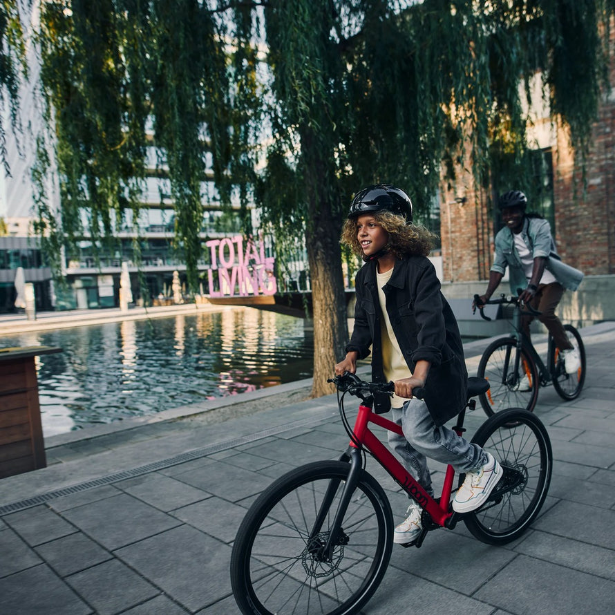 Enfant de 6 a 8 ans roulant sur velo woom explore 4 20 pouces rouge en milieu urbain avec casque