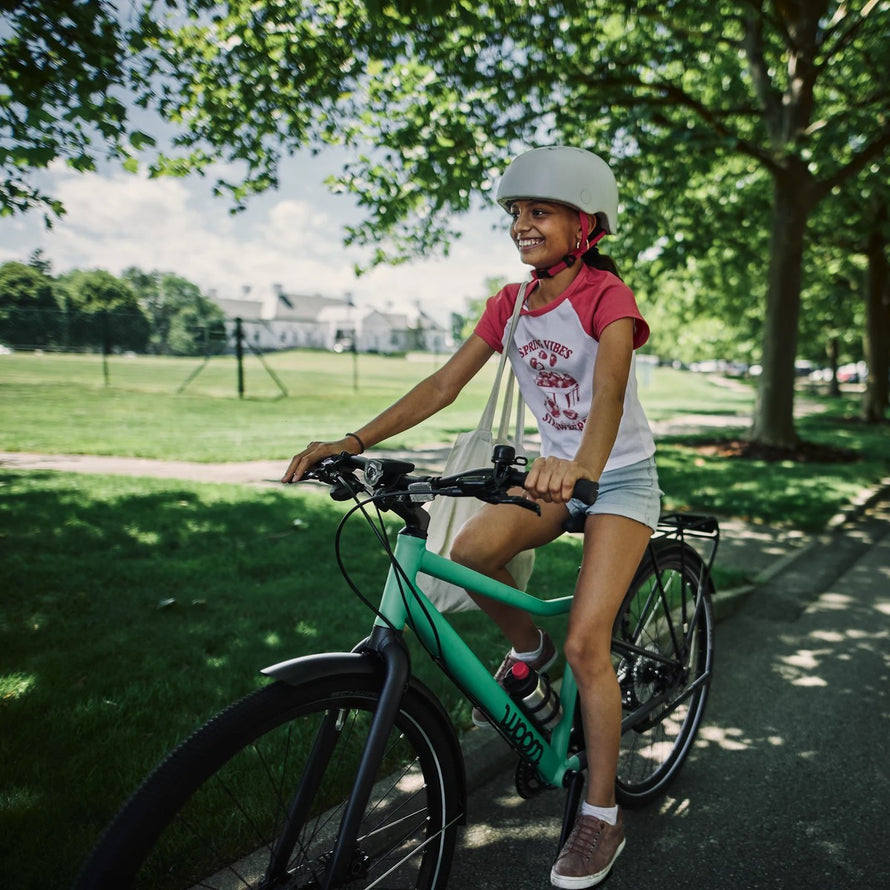 Enfant souriant sur velo woom explore 4 20 pouces vert en balade en plein air pour 6 a 8 ans